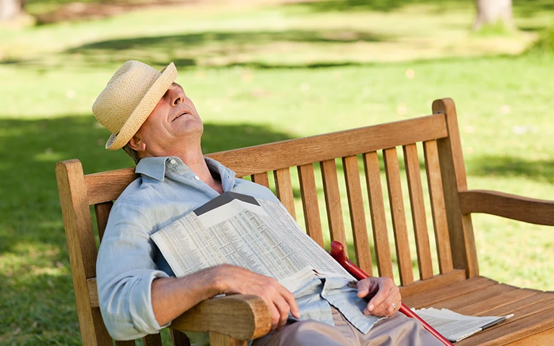 איש מבוגר ישן על ספסל עם עיתון