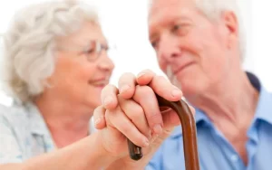 זוג מבוגר מחזיק ידיים עם מקל הליכה