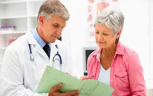 אישה מבוגרת יושבת עם הרופא שלה ומסתכלים על מסמכים